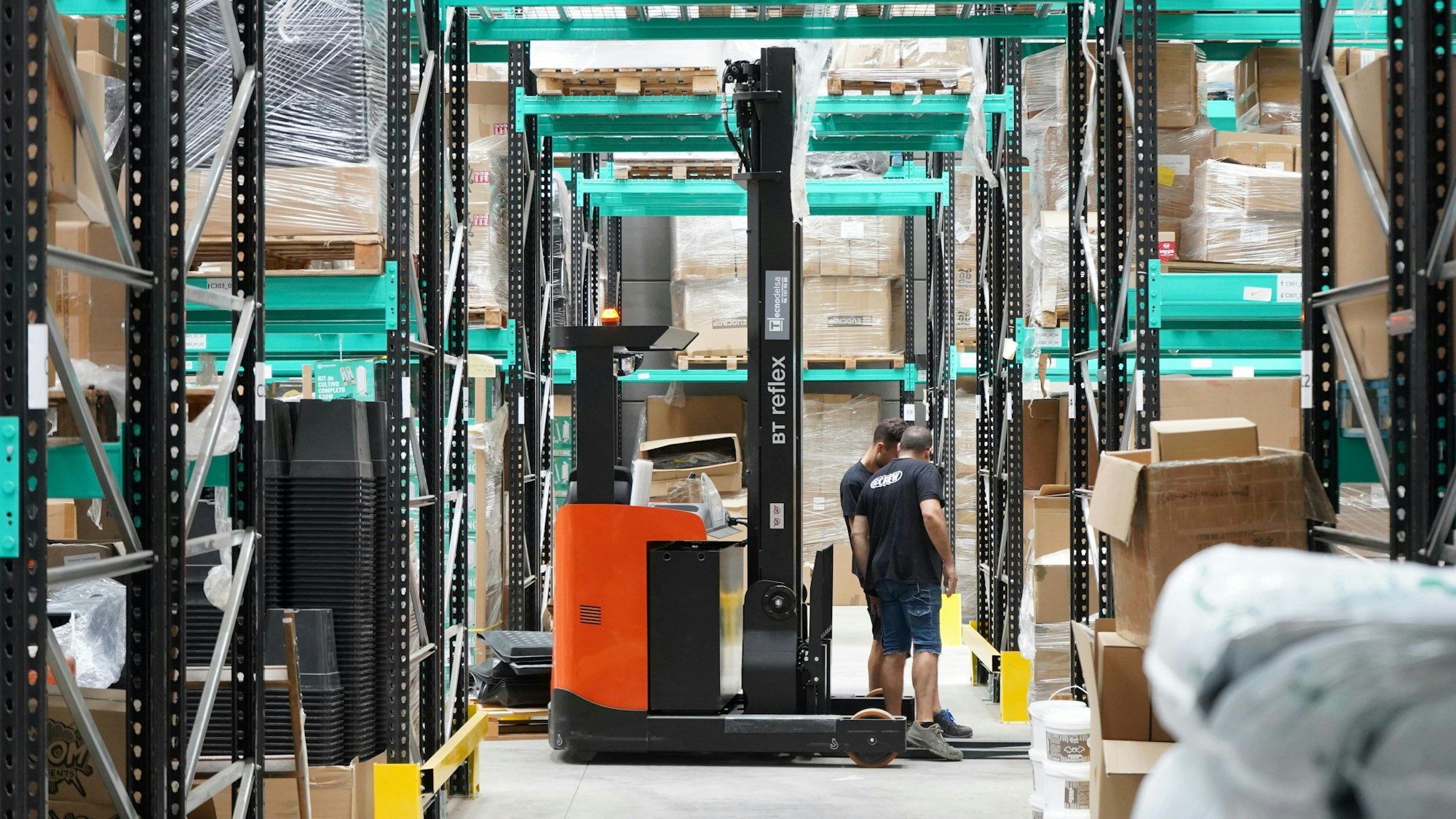 Warehouse worker with a forklift between fully stocked racks